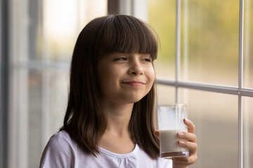 Happy 7s girl kid with funny milky mustache enjoying fresh wholesome milk, drinking dairy beverage...