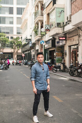 Portrait of asian young handsome man in denim shirt standing on the street and looking at camera with copy space. Chinese people