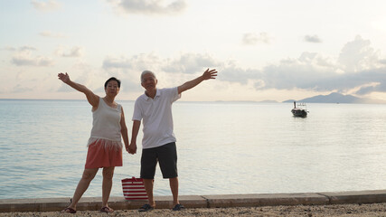 Fototapeta premium Asian elder senior couple retirement fun beach ocean trip healthy relationship and financial