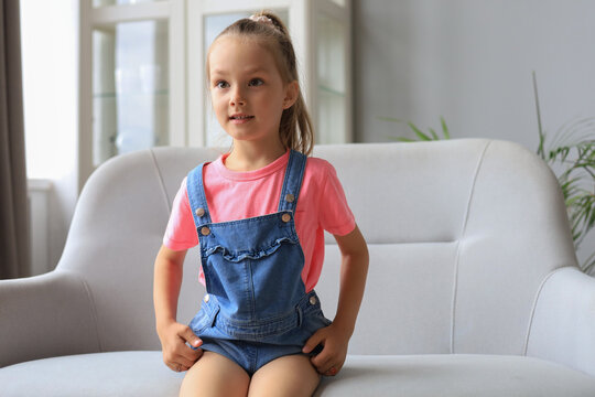 Excited child looking at camera while sitting in living room at home.