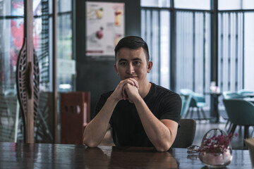 Asian young handsome man sitting in coffee shop and smiling. Chinese guy, millennials life, lifestyle in the big city, Modern Asia, coffee break