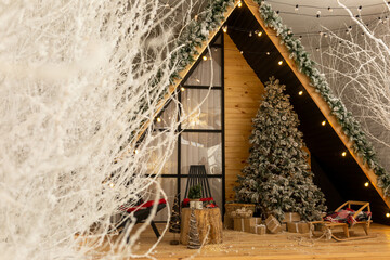 Wooden holiday house in a snowy forest, with a Christmas tree on the terrace