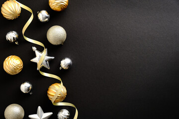 Christmas greeting card template. Christmas golden and silver balls and baubles on dark black background. Flat lay, top view, copy space