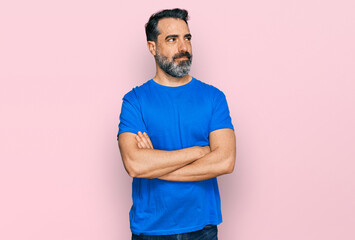 Middle aged man with beard wearing casual blue t shirt smiling looking to the side and staring away...