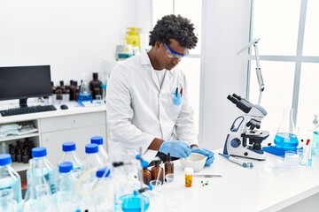 Naklejka premium Young south east man wearing scientist uniform making experiment at laboratory