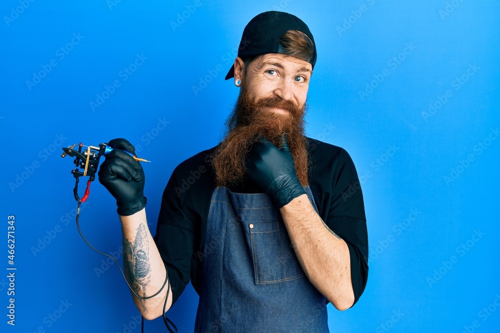 Poster redhead man with long beard tattoo artist wearing professional uniform and gloves looking confident 