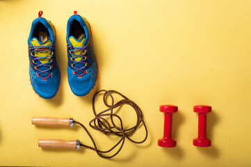 Equipment for fitness. Sports shoes on a fitness mat. Do fitness with dumbbells and skipping rope.