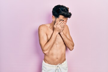 Fototapeta premium Young hispanic man wearing swimwear shirtless with sad expression covering face with hands while crying. depression concept.
