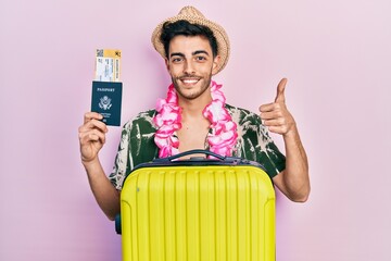 Young hispanic man wearing summer style and hawaiian lei holding passport and boarding pass smiling...