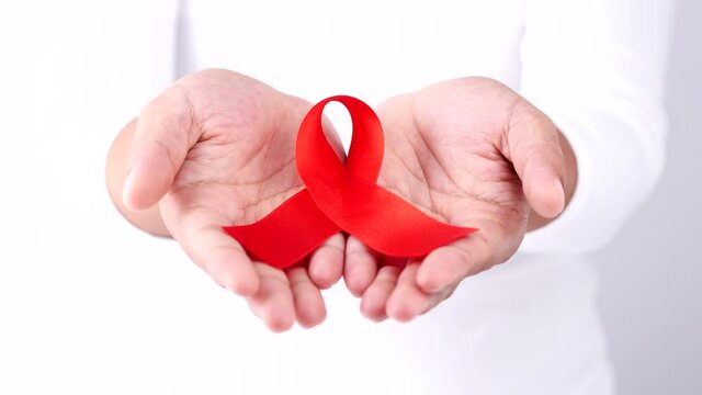 Close-up hands holding red aids awareness ribbon on white background, Concept of World Aids Day, HIV, Cancer Awareness, Healthcare, Medicine.