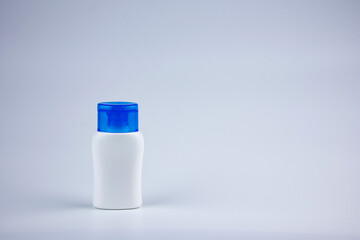 White bottle with blue cap on gray background. Products for packing liquids. Product advertising, empty bottles for packing