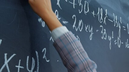 Female hand with chalk. Math faceless teacher writes examples for schoolchildren on blackboard. Student, pupil girl solves system of equations on chalkboard. Algebra, mathematics in classroom - Powered by Adobe