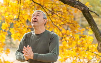 Mature European man with a good mood, outdoor portrait at autumn park . The concept of life after 50 years	