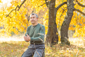 Mature European man with a good mood, outdoor portrait at autumn park . The concept of life after 50 years	