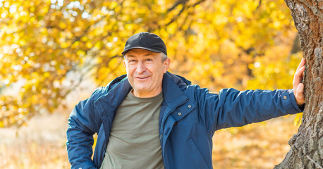 Mature European man with a good mood, outdoor portrait at autumn park . The concept of life after...