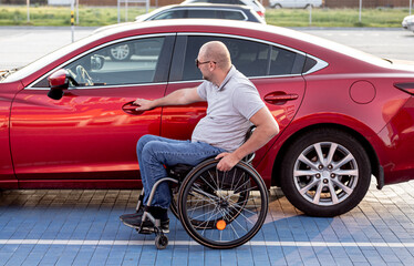 Fototapeta na wymiar person with a physical disability getting in red car from wheelchair