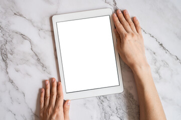digital tablet computer in female hands with vertical white blank digital screen for mockup or space for text on a gray marble background. top view, flat lay