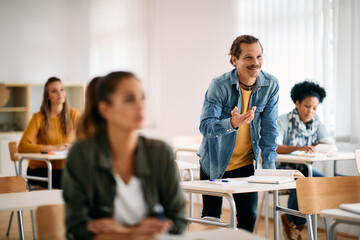 Happy male student talks while attending lecture in the classroom.