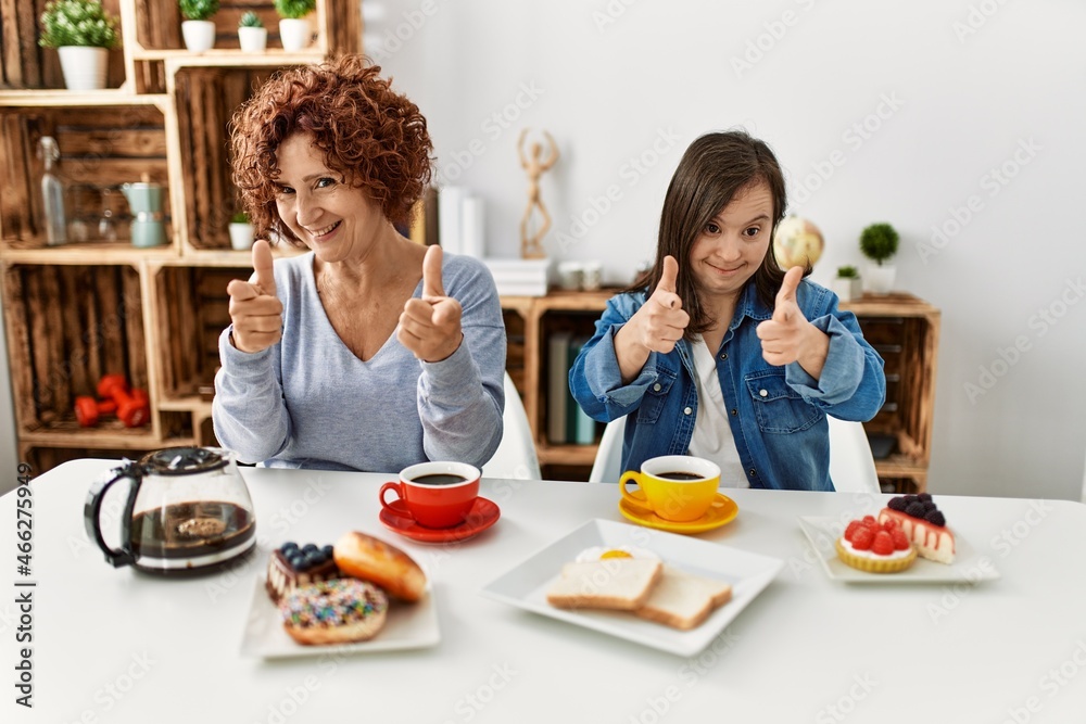 Canvas Prints Family of mother and down syndrome daughter sitting at home eating breakfast pointing fingers to camera with happy and funny face. good energy and vibes.