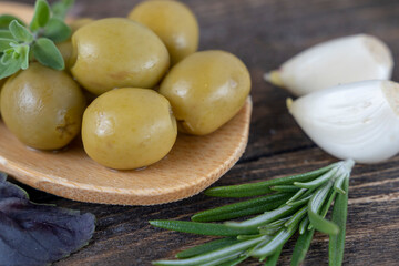 olives with spices and rosemary in a wooden spoon