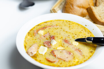 Traditional polish sour soup with sausage and eggs in ceramic bowl