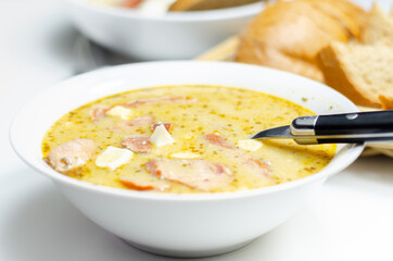 Traditional polish sour soup with sausage and eggs in ceramic bowl