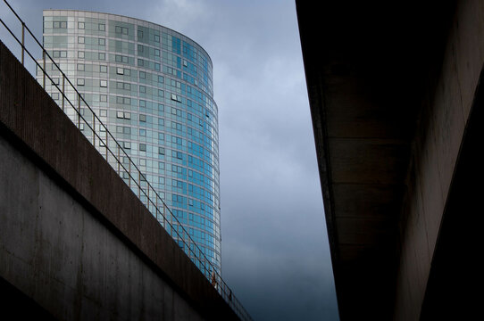 Obel Tower, Belfast as seen from under the River Lagan bridges against a moody sky.