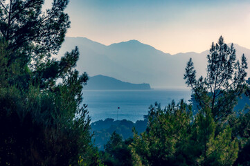 Misty morning views of Yildiz Island and Marmaris Milli Parki from a hill behind Turunc showing a Turkish flag in the centre surrounded by pine trees.