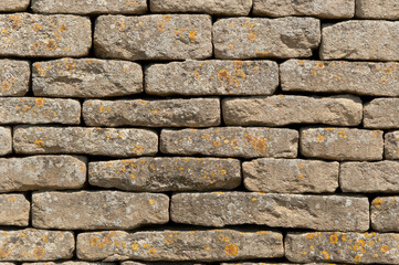 Sideways on shot of a random bond drystone wall made from flat grey blocks with lichen growth
