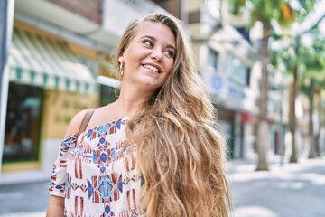 Young blonde girl smiling happy standing at the city.