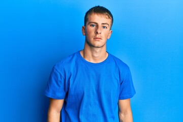 Fototapeta premium Young caucasian man wearing casual blue t shirt relaxed with serious expression on face. simple and natural looking at the camera.