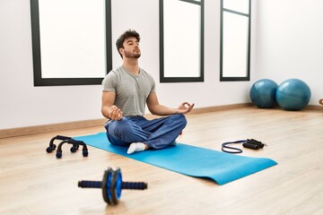 Young hispanic sporty man training yoga at sport center.