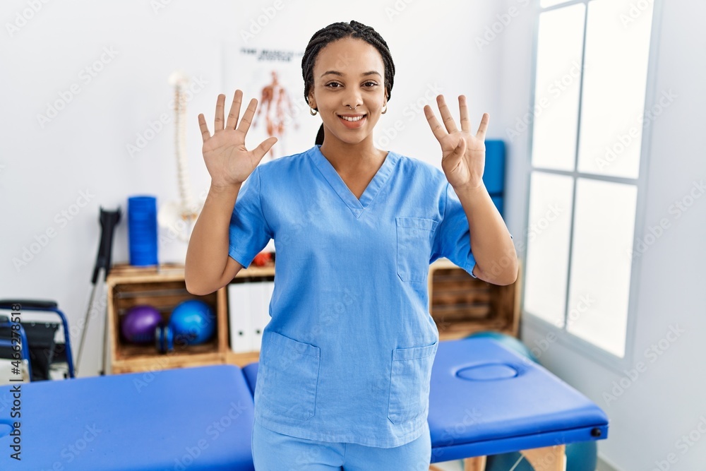 Sticker young african american woman working at pain recovery clinic showing and pointing up with fingers nu