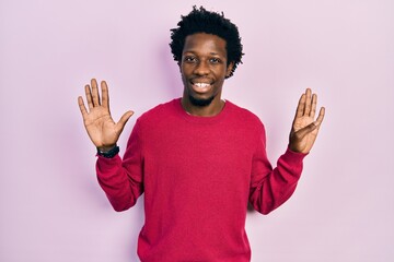 Naklejka premium Young african american man wearing casual clothes showing and pointing up with fingers number nine while smiling confident and happy.