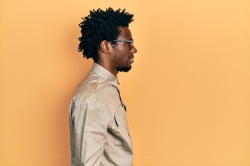 Fototapeta na wymiar Young african american man wearing casual clothes and glasses looking to side, relax profile pose with natural face with confident smile.