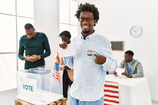 Young american voter man smiling happy pointing with finger to i voted badge at electoral center.