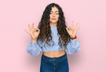 Young hispanic girl wearing casual clothes relaxed and smiling with eyes closed doing meditation gesture with fingers. yoga concept.