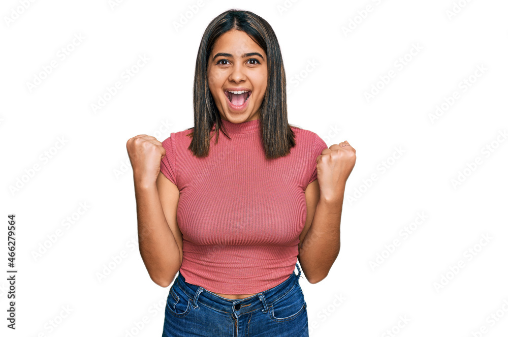 Poster Young hispanic girl wearing casual t shirt celebrating surprised and amazed for success with arms raised and open eyes. winner concept.