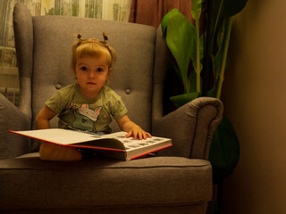 Fototapeta na wymiar little girl leafing through a book while sitting in a chair life style
