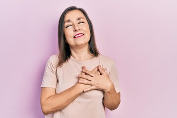 Middle age hispanic woman wearing casual clothes smiling with hands on chest with closed eyes and grateful gesture on face. health concept.