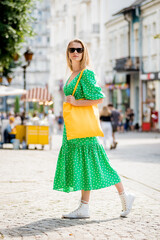 Young beautyful woman with yellow linen eco bag on city background.