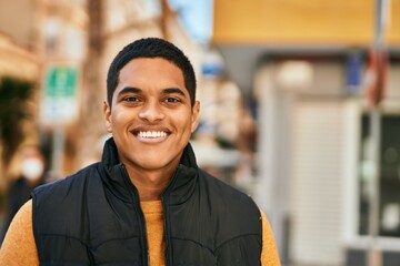 Young latin man smiling happy standing at the city