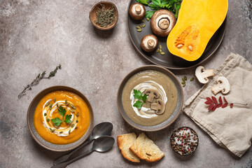 Pumpkin and mushroom cream soup in a bowl on a brown grunge background. Vegan or vegetarian lunch. Warm winter soup. Top view, flat lay.