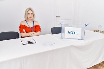 Young caucasian woman at political election sitting by ballot skeptic and nervous, disapproving...