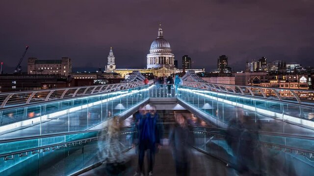 London night timelapse view across the Thames river with the Millenium Bridge and St Pauls cathedral in the center. Beautiful night life in London.