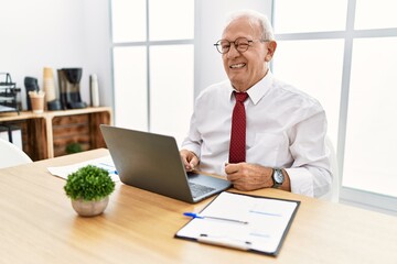Senior man working at the office using computer laptop winking looking at the camera with sexy...