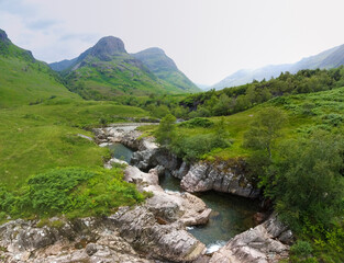Fototapeta premium Aerial panoramic view of the waterfalls on the River Coe near Allt-na-ruigh with the Three Sisters in the background, Scotland