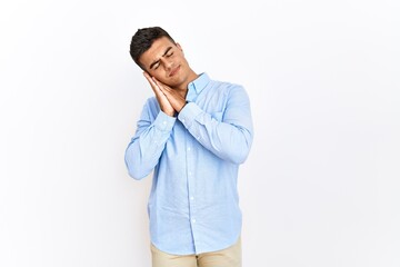 Young hispanic man wearing business shirt standing over isolated background sleeping tired dreaming and posing with hands together while smiling with closed eyes.