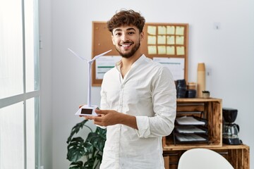 Naklejka na ściany i meble Young arab man smiling confident holding. windmill at office
