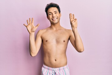 Fototapeta premium Young handsome man wearing swimwear shirtless showing and pointing up with fingers number eight while smiling confident and happy.